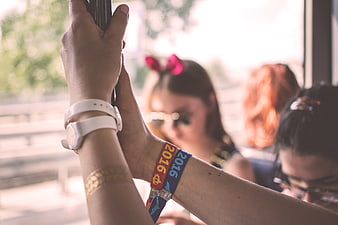 Close-up of hands holding bus pole with 2016 wristbands