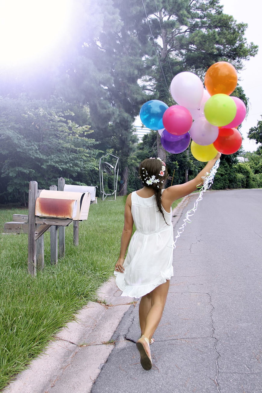 Woman in White Dress Walking with Colorful Balloons