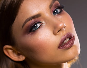 Close-up portrait of woman with glamorous purple makeup