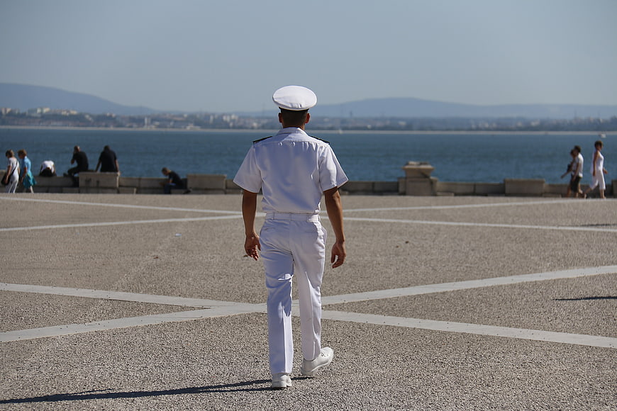 Sailor in white uniform walking on a riverside promenade