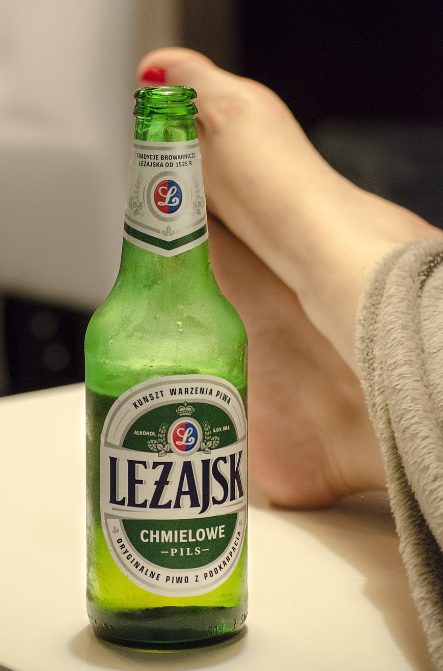 Cold Lezajsk beer bottle with relaxed foot in background