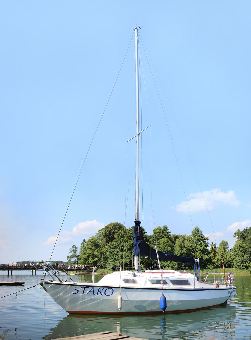 White sailboat named Stako docked on a calm lake