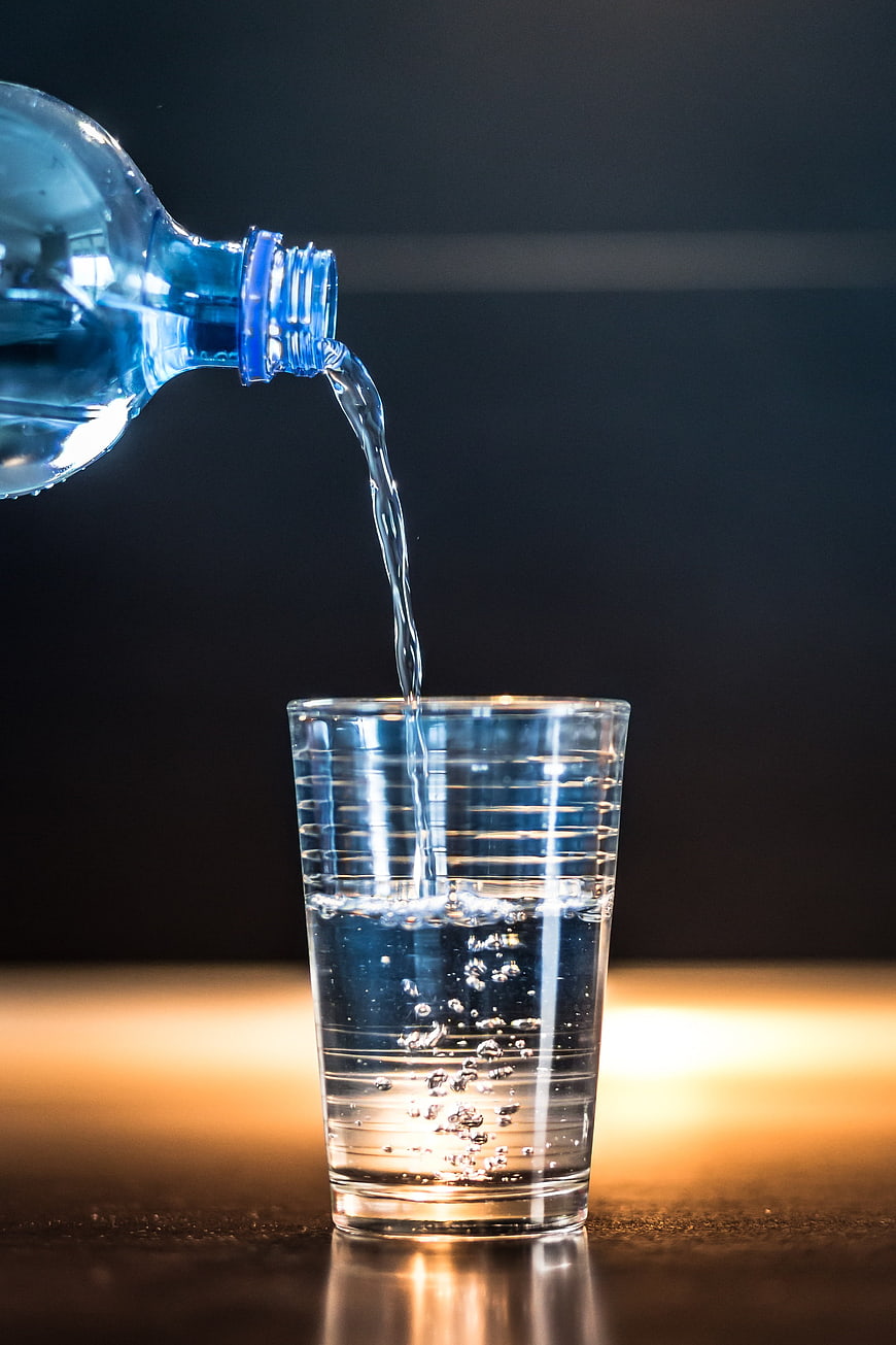 Pouring Water from Plastic Bottle into Glass