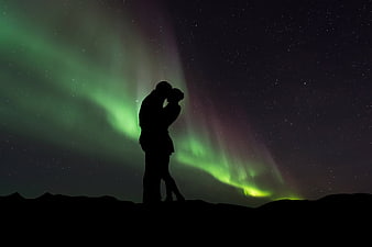 Silhouette of a couple kissing under the northern lights
