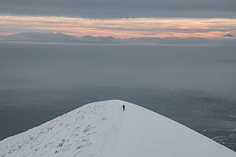 Lone Hiker on Snowy Mountain Ridge at Sunset