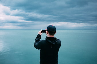 Man Taking Photo of Ocean with Smartphone