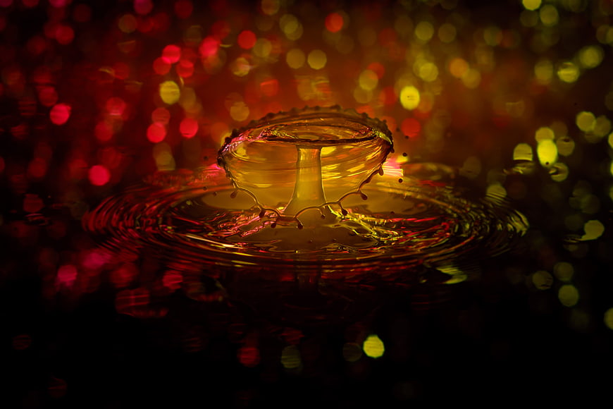 Golden liquid splash with colorful bokeh background