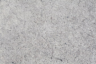 Close-up of rough gray concrete surface texture with cracks and aggregate
