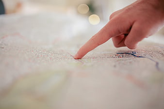 Close-up of finger pointing at location on paper map