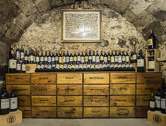 Wine cellar with bottles on wooden crates and stone arch