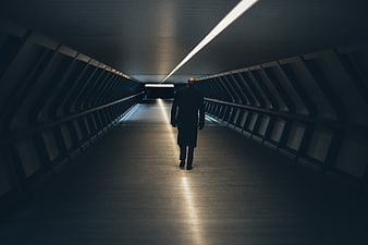 Silhouette of man walking down dark modern tunnel