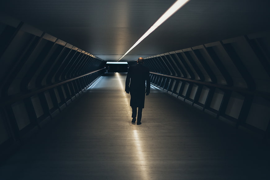 Silhouette of man walking down dark modern tunnel