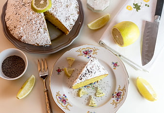 Lemon Cake Slice With Powdered Sugar And Fresh Lemons On Floral Plate