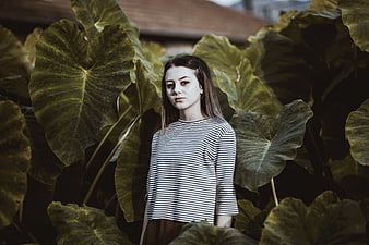 Young Woman Standing Among Large Green Leaves