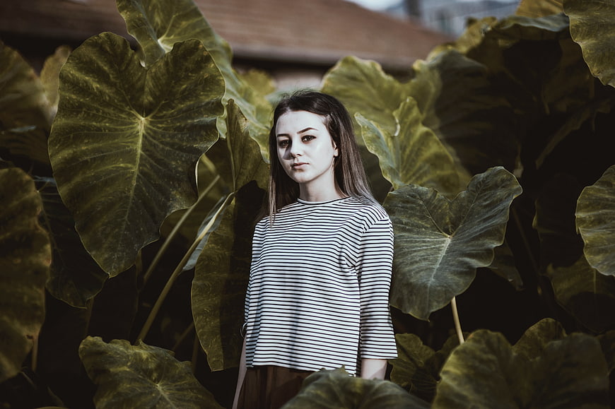 Young Woman Standing Among Large Green Leaves