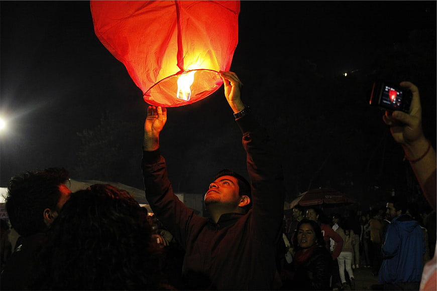 Man Releasing Glowing Red Sky Lantern at Night Festival