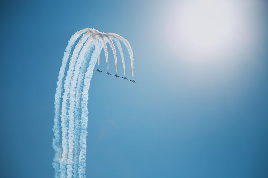 Aerobatic jets performing a loop with smoke trails in blue sky