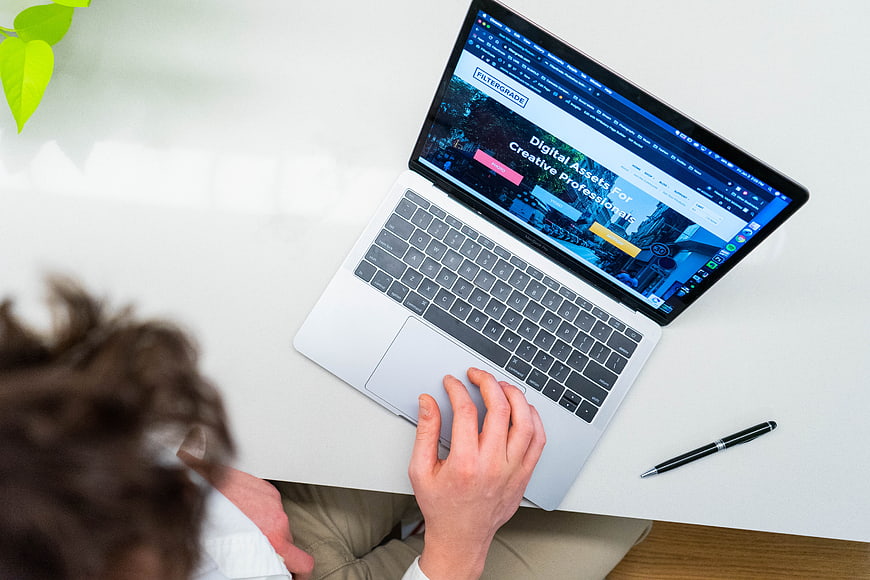 Overhead view of person typing on laptop at white desk