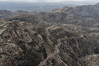 Winding Mountain Road Through Arid Hills with Distant City View