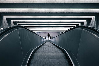 Silhouette of Man Walking Up Escalator in Modern Subway Station