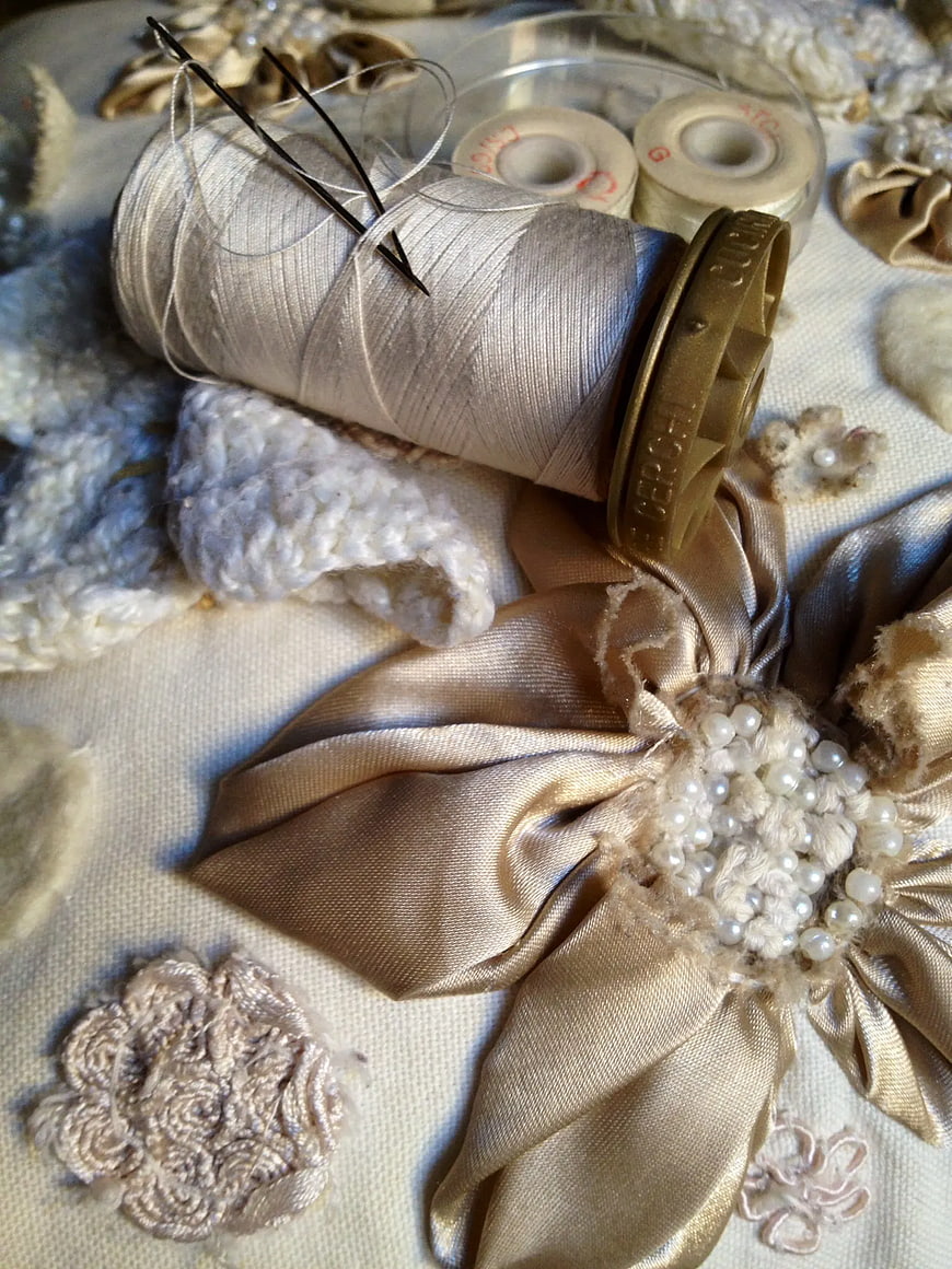 Vintage sewing supplies with spool of thread and pearl flower