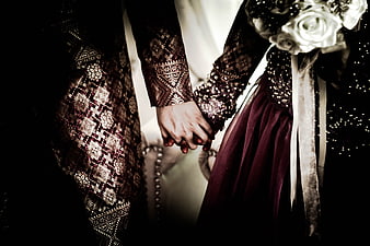 Close-up of wedding couple holding hands in elegant attire
