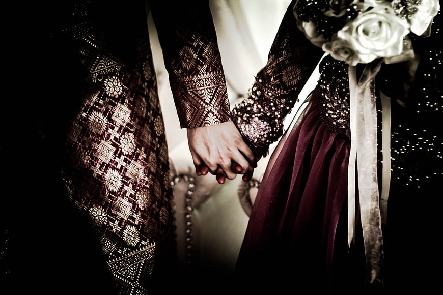 Close-up of wedding couple holding hands in elegant attire