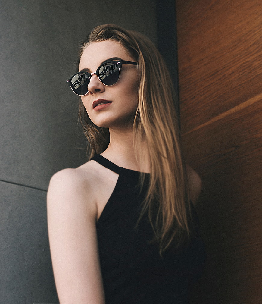 Stylish Woman Wearing Sunglasses Against Textured Wall