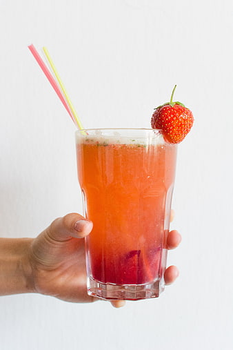 Hand holding strawberry basil lemonade with straws