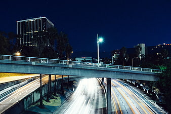 Night highway traffic light trails under city overpass