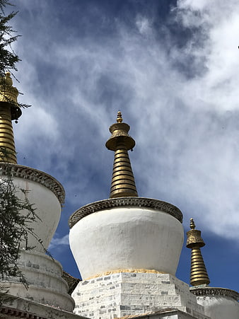 White Buddhist Stupas with Golden Spires Against Blue Sky