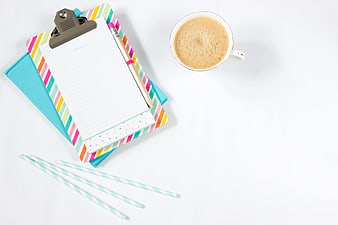 Flat lay of colorful clipboard, coffee cup, and stationery on white background