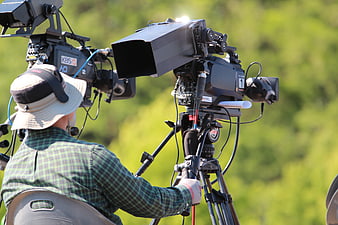 Cameraman operating professional broadcast video camera outdoors
