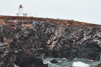 White Lighthouse on Rocky Coastal Cliff Overlooking Ocean