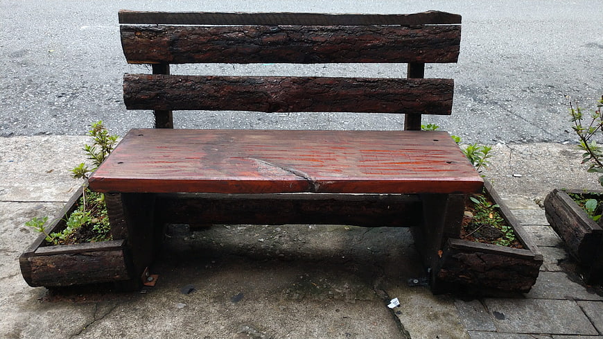 Rustic wooden bench with planter boxes on concrete