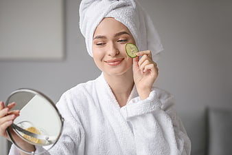 Woman with cucumber slice on face doing skincare routine