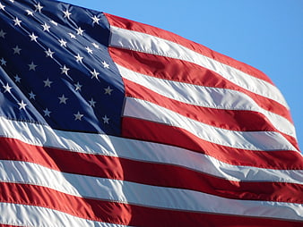 Close-up of waving American flag against blue sky