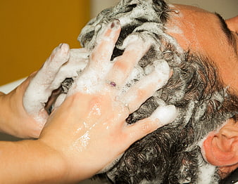 Close-up of hands massaging shampoo foam into wet hair