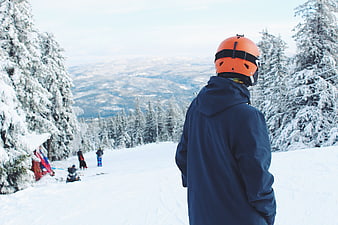 Skier in Orange Helmet Overlooking Snowy Mountain Slope