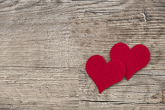 Two red felt hearts on rustic wooden background