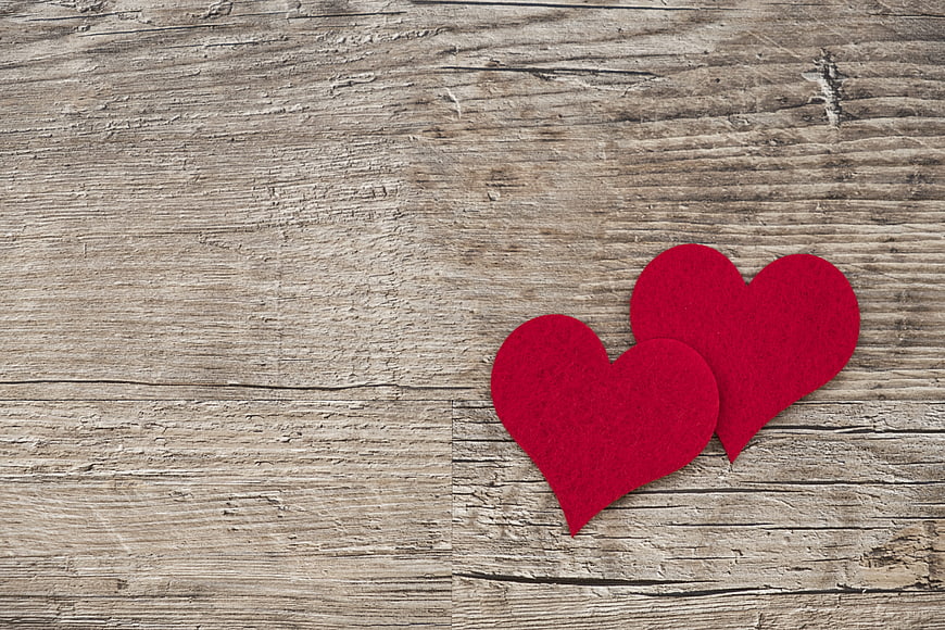 Two red felt hearts on rustic wooden background