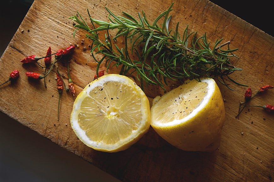 Sliced Lemon, Rosemary, and Chili Peppers on Rustic Wooden Cutting Board