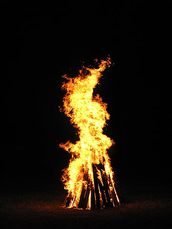 Tall Bonfire Burning Brightly Against Black Night Sky