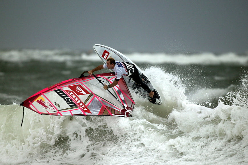 Windsurfer performing dynamic wave jump in ocean