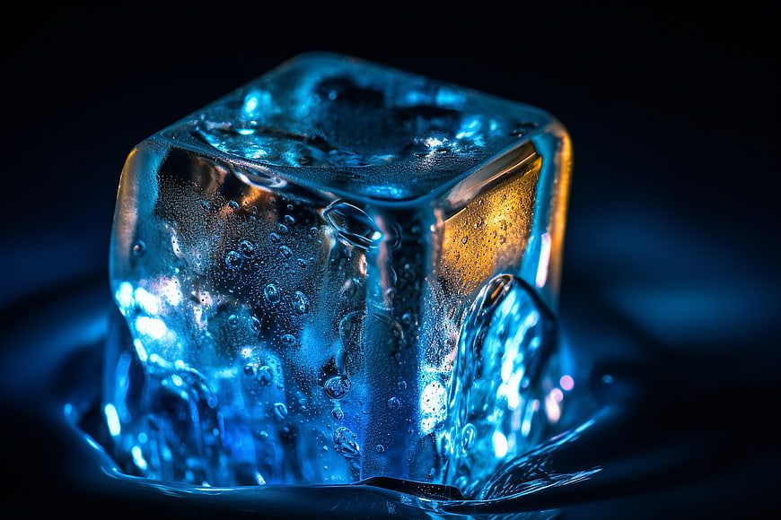 Macro shot of glowing blue ice cube with bubbles