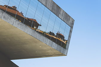 Modern concrete building with glass facade reflecting traditional rooftops