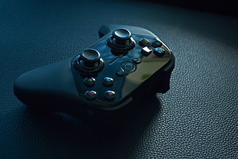 Glossy Black Game Controller on Textured Blue Surface