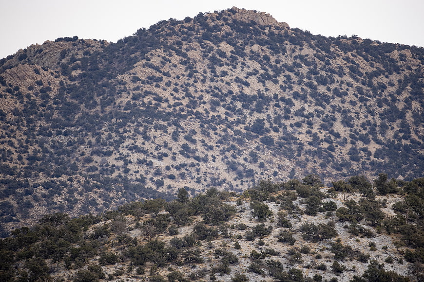 Arid rocky mountain landscape with scattered shrubs and dry terrain