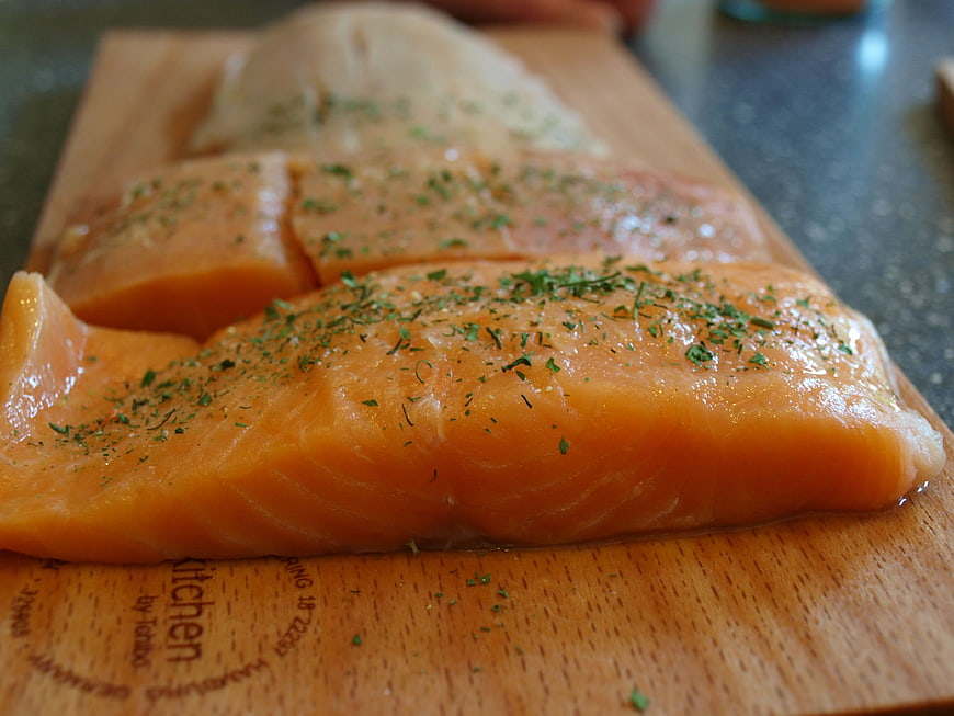 Raw Salmon Fillets Seasoned With Herbs On Wooden Cutting Board