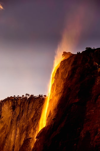 Fiery Golden Waterfall Illuminated by Sunset Light on Granite Cliff